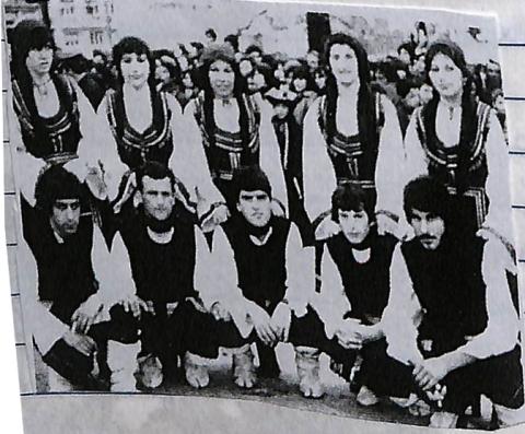 Ομαδική φωτογραφία, ορθίες είναι οι γυναίκες και ακριβώς απο κάτω γονατιστοί οι άντρες. Όλα τα άτομα στην φωτογραφία φορουν παραδοσιακά ενδύματα. Ασπρόμαυρη φωτογραφία